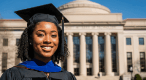 A close-up portrait of a confident, young Black woman in academic attire, smiling proudly outside the Massachusetts Institute of Technology campus, with the iconic architecture in the background, vibrant colors, photorealistic, 4K, HDR, cinematic lighting, ultra detailed, award-winning photography.